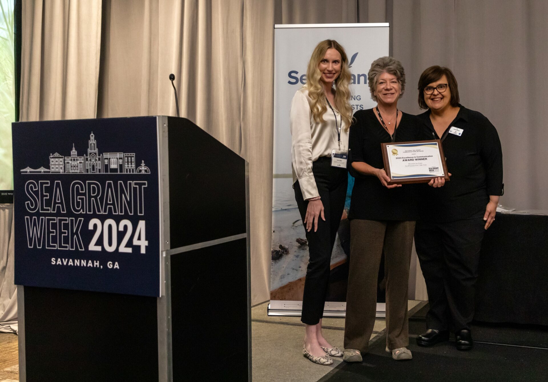 Science communicator Marie Zhuikov poses with a communications award at Sea Grant Week alongside two other people