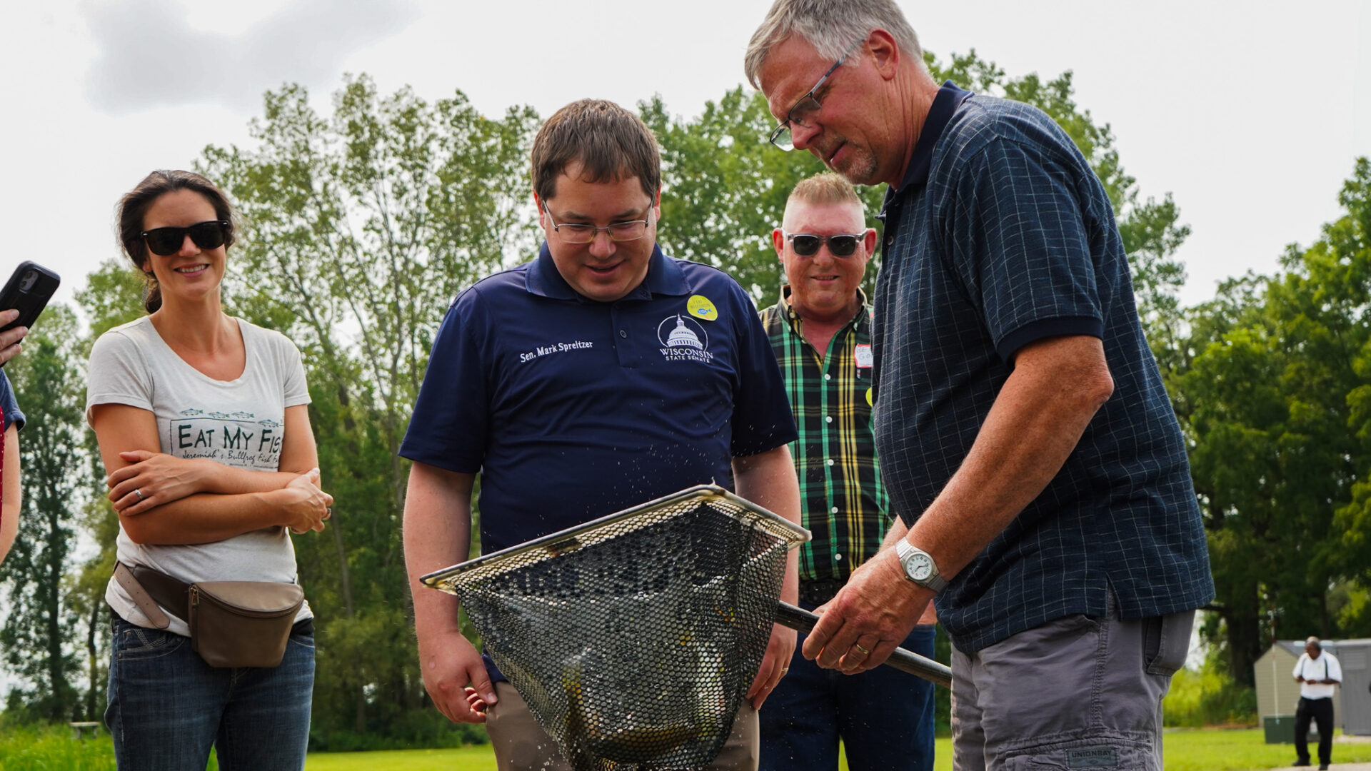 Fish farmer doug Sackett nets several perch from him pond as the tour group watches
