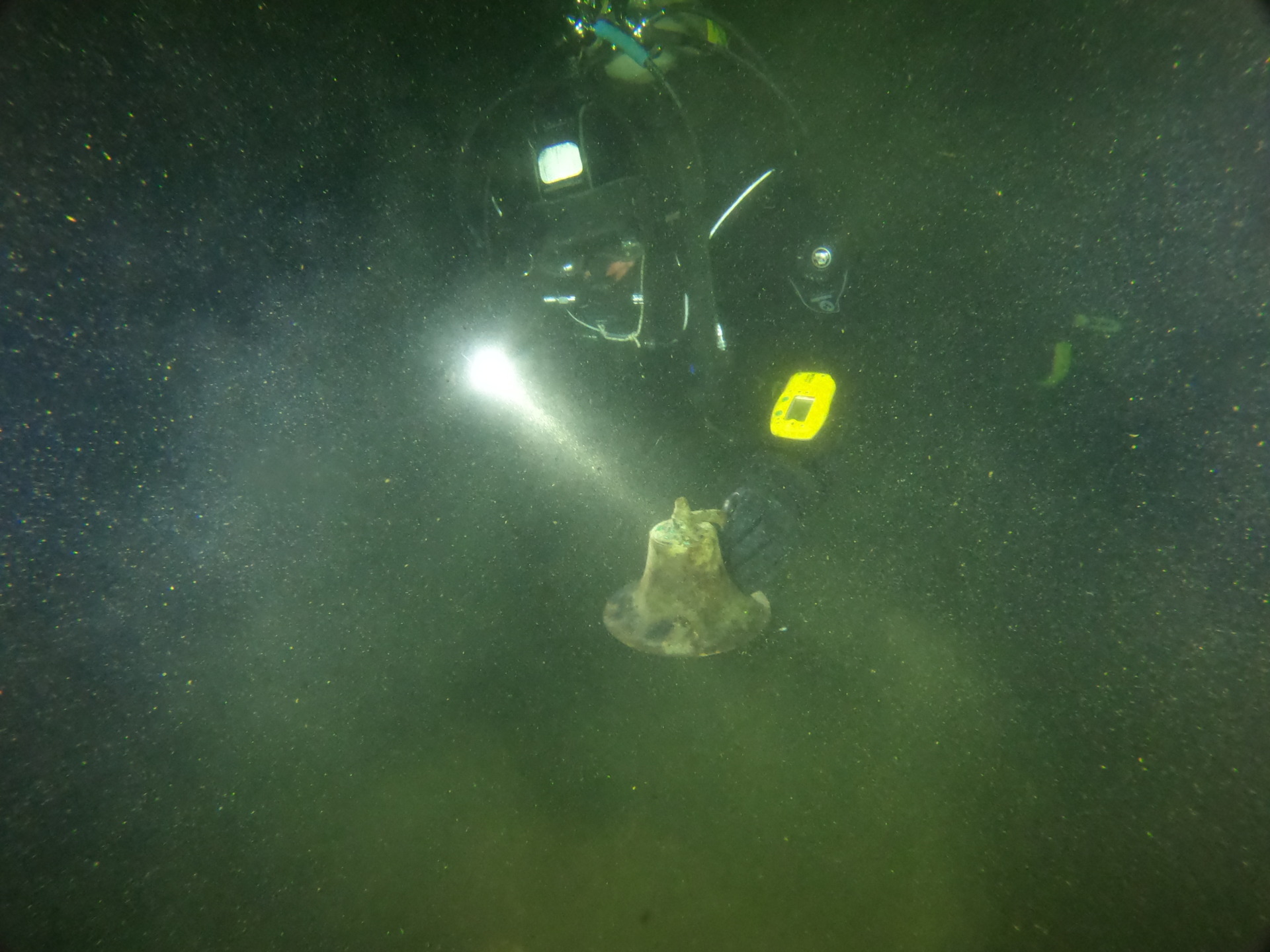 Diver Tim Pranke holds up the bell from the shipwreck of the Little Harbor launch