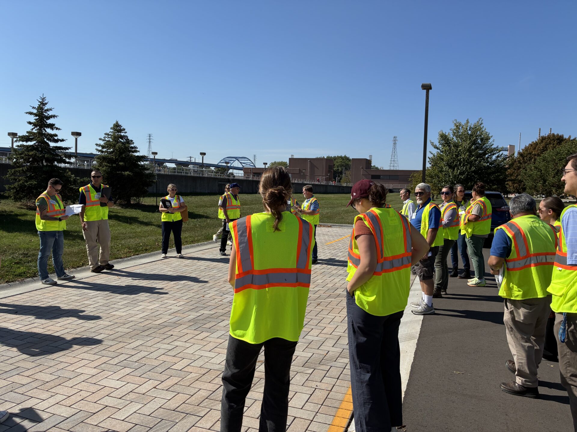 A tour group in high visibility yellow vests looks at a section of permeable pavement