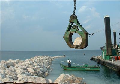 Large crane placing large rocks on a shoreline