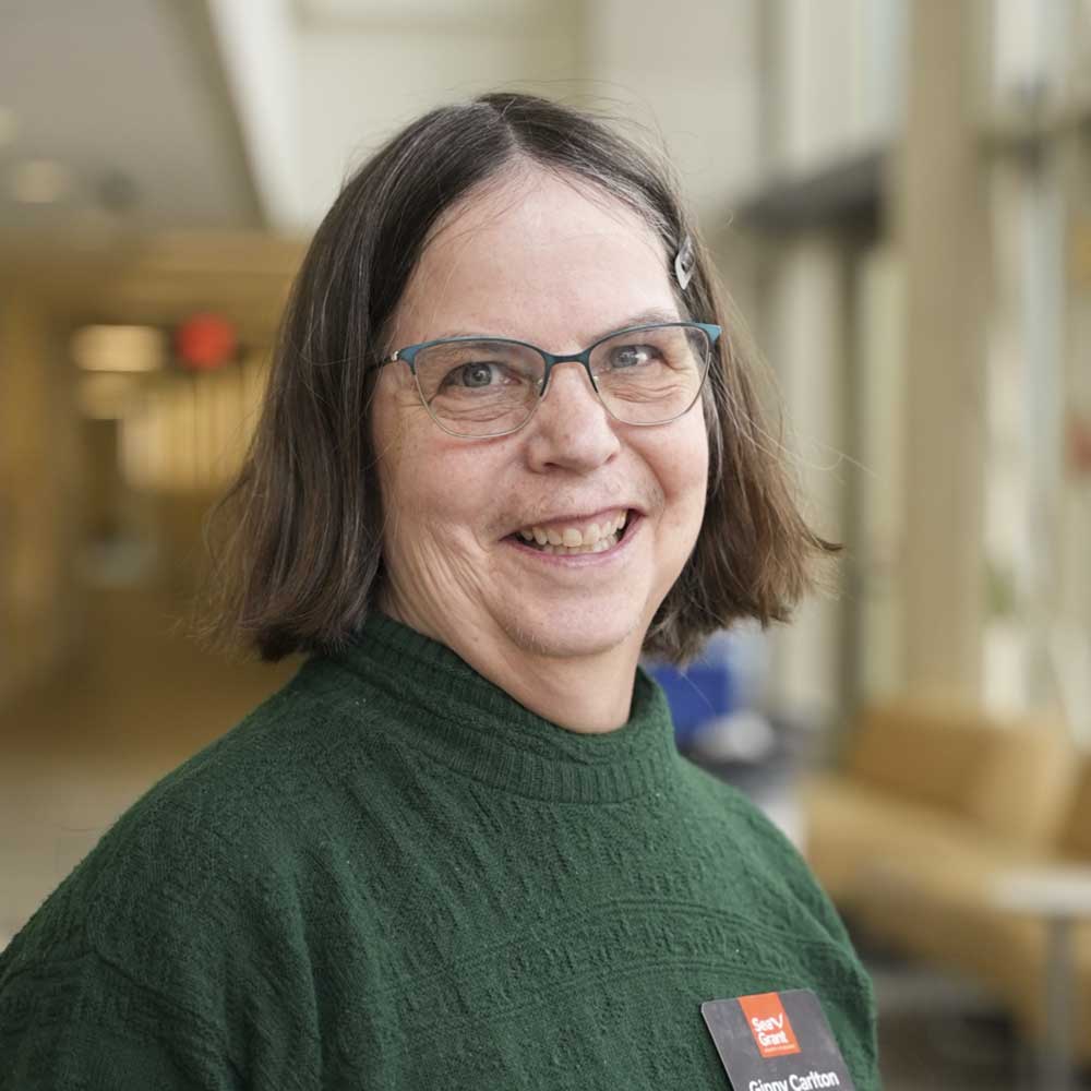 A woman with short dark hair, glasses, and a green sweater with a Sea Grant name tag poses for a photo.